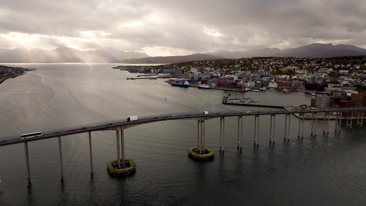 Luftbild-Drohnenpanorama des Verkehrs auf der langen Tromsø-Brücke zur Stadt Tromsø, dramatischer Himmel. Norwegen
