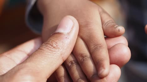 las manos del niño sostenidas por un adulto