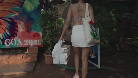 slow motion shot of a young indian artist entering an art gallery, with some of her artworks and other art tools