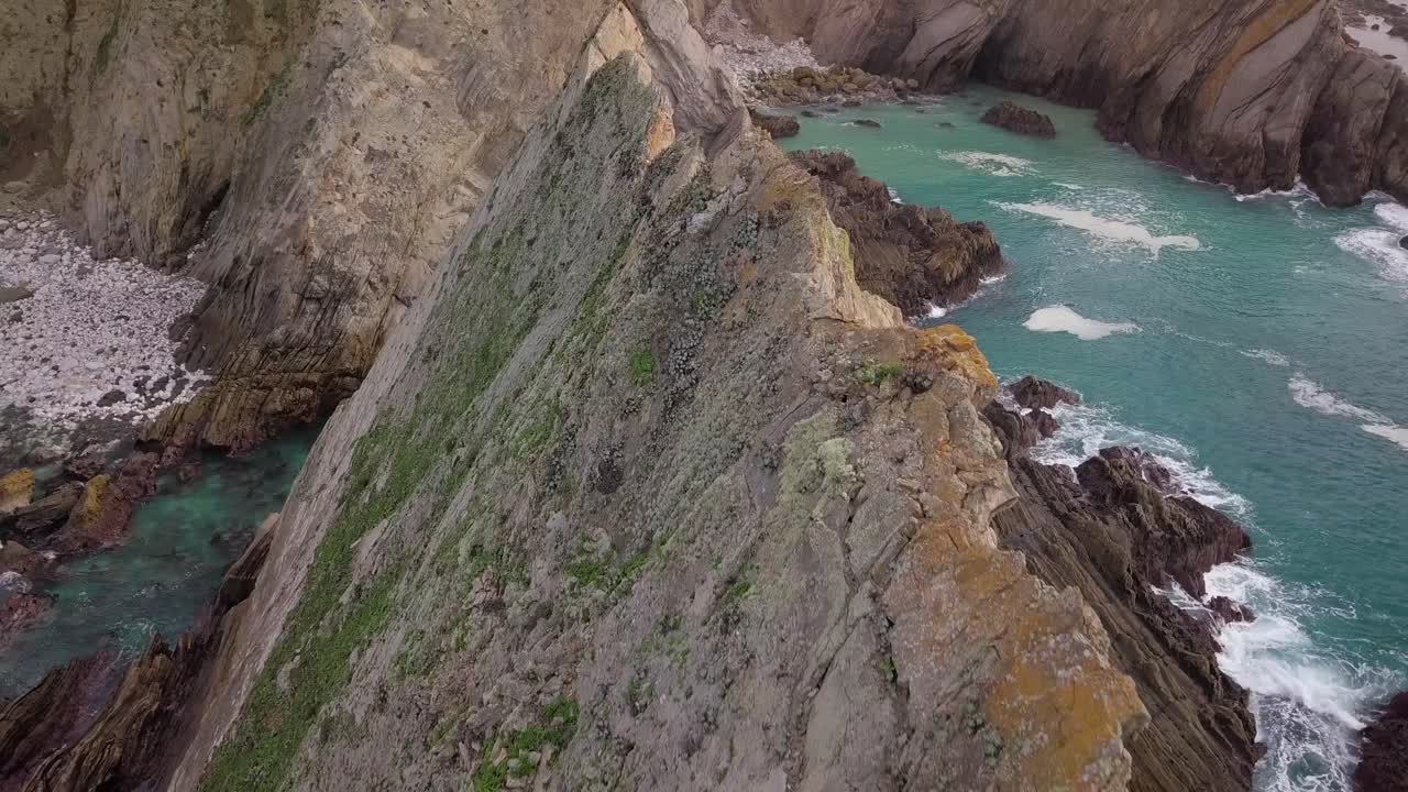 drone volando hacia acantilados sobre picos geológicos en la costa de california en el océano pacífico