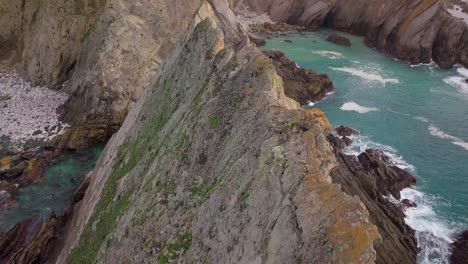 drone flying towards cliffs over geological spikes on the california coast on the pacific ocean