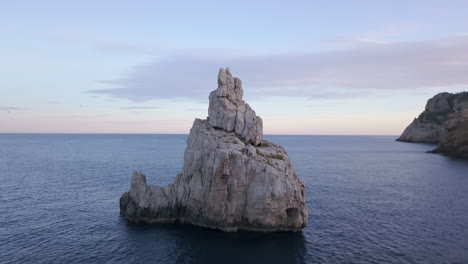 drone orbit of benirrás rock with birds passing by the painted sky