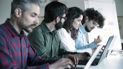 side view of focused developers working with laptops