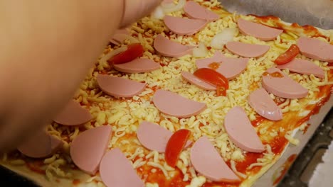 la cocinera casera está vertiendo cebollas recién picadas en pizza casera