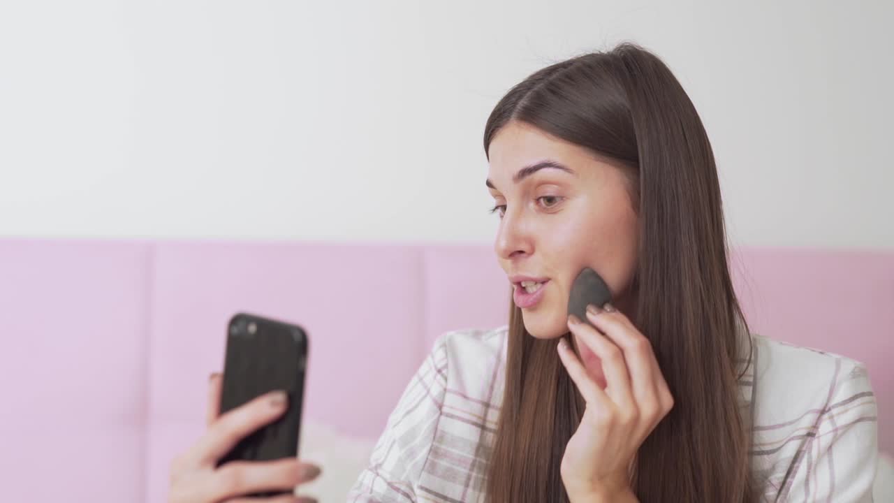 hermosa chica hablando por teléfono en las redes sociales sobre una esponja de maquillaje