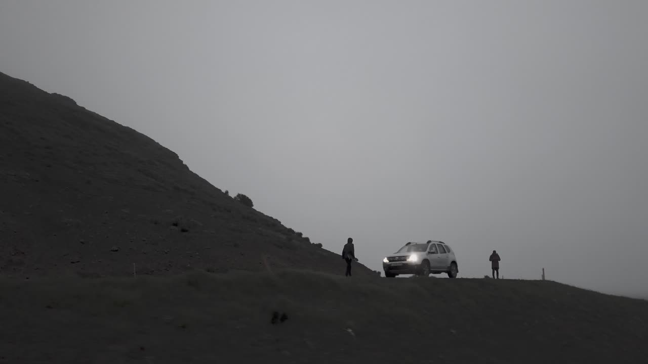 아이슬란드의 안개가 자욱하고 극적인 풍경 속에서 구불구불한 도로를 타고 내려가는 스케이터의 드론 샷