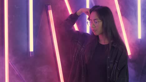 young beautiful girl in glasses. smoke and colored light background, studio