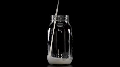 la leche llena gradualmente los frascos de vidrio con pajitas