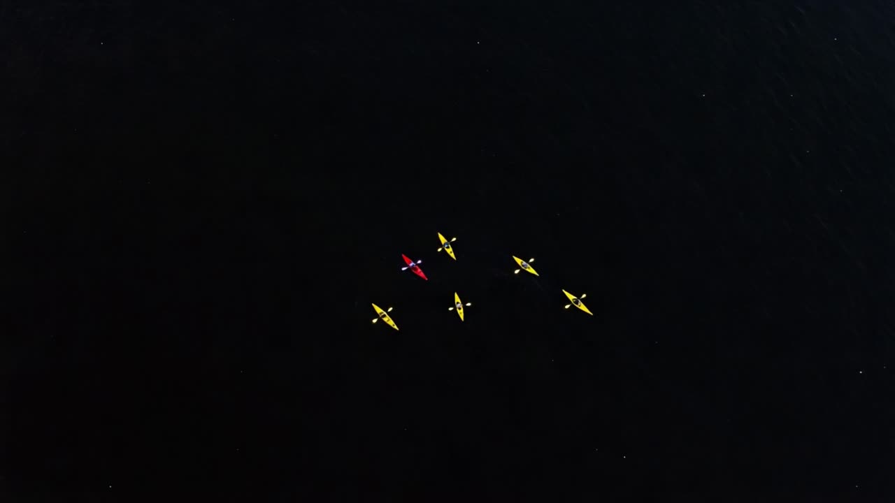 Aerial View of Kayakers in Formation on Dark Waters, Showcasing the Colorful Canoes and the Serenity of Nature during a Calm Day