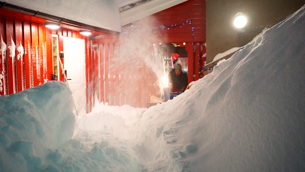 Man operates snow blower, cutting through heavy drifts of snowfall
