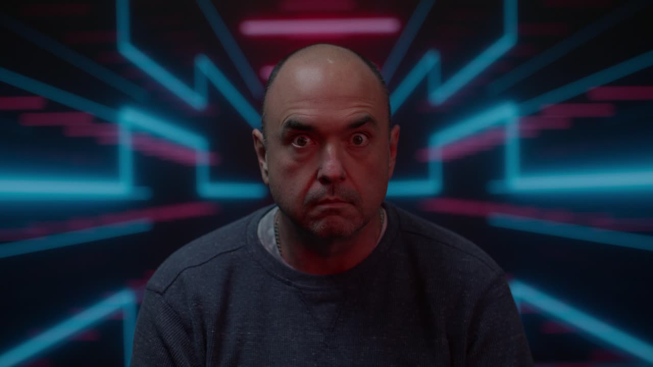 hombre blanco de mediana edad mirando a la cámara con una mirada amenazante con un fondo colorido en movimiento