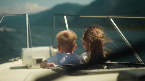 lovely kids lean out of sailboat hatch having trip across ocean on nice day. happy boy and girl ride yacht on summer vacation. amazing journey