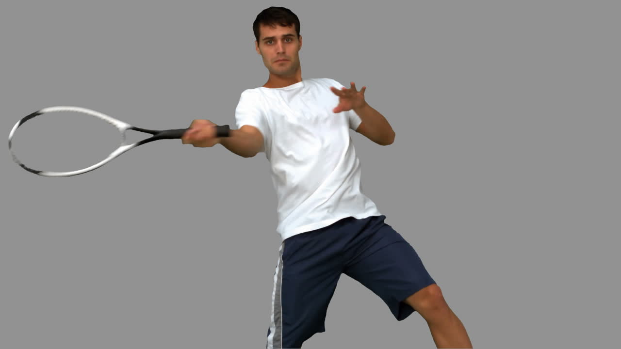 Man training while playing tennis on grey screen