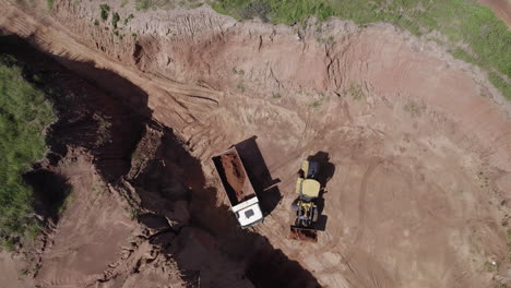 un disparo de drone de un excavador cargando en un camión en un desarrollo de propiedad