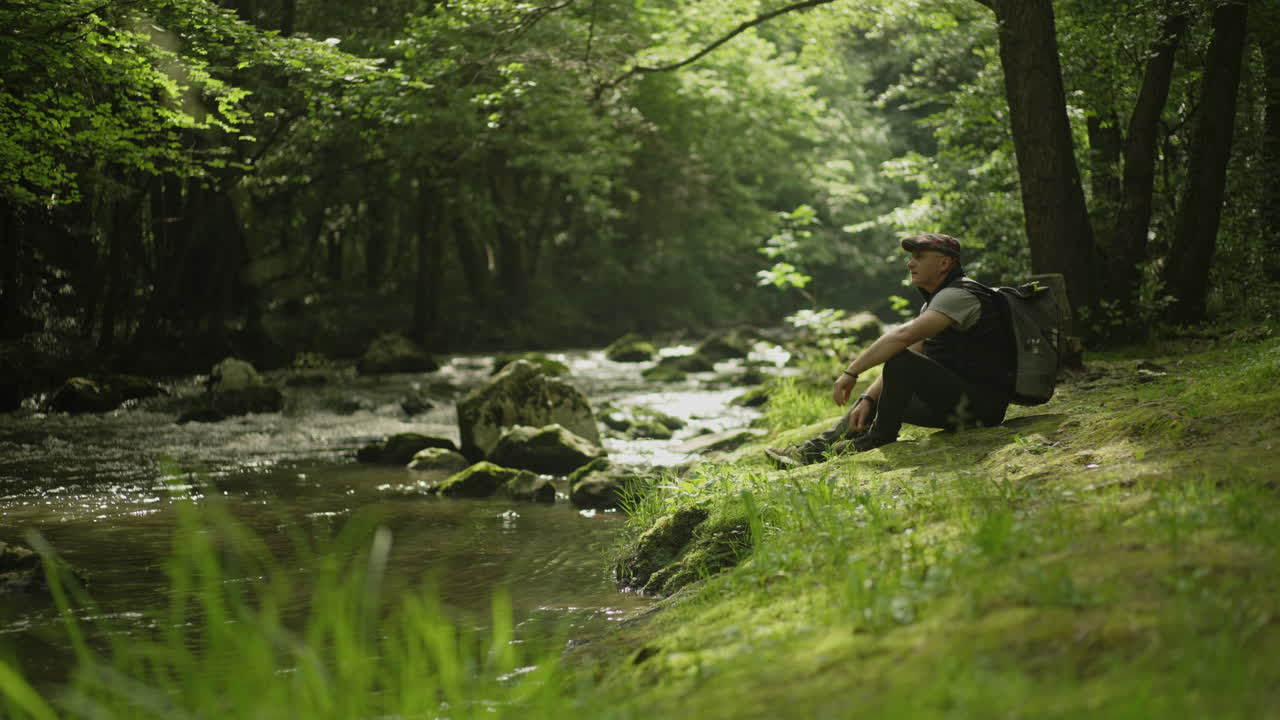 Man sitting by a river in a forest