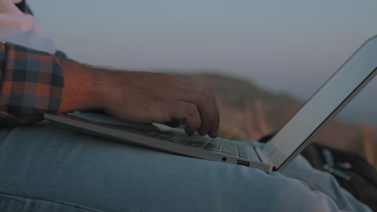 Primer plano de un hombre escribiendo en una laptop.