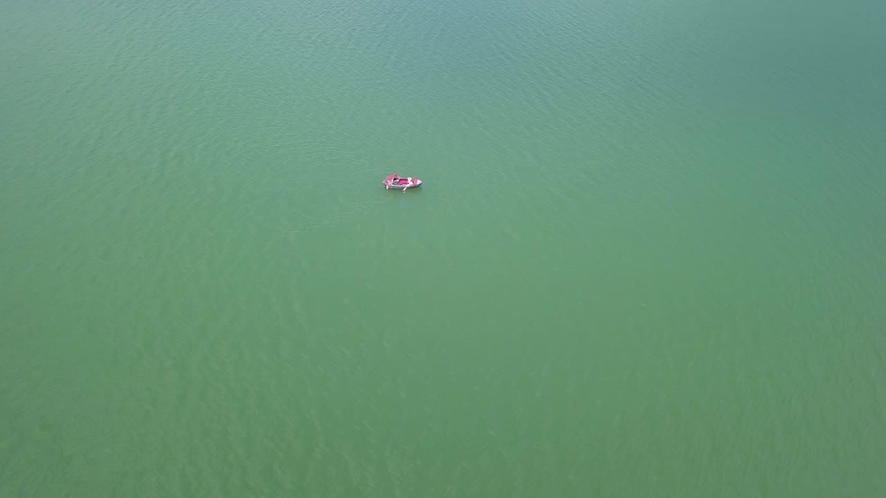 fotografía de aproximación aérea de un lago con un barco flotando en el medio, fotografía de arriba hacia abajo