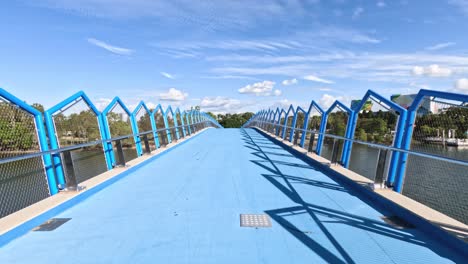 persona caminando a través de un puente peatonal azul