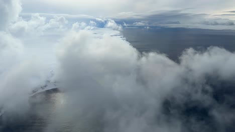 aerial view above the clouds in finnmark revealing a nice coastline with cliffs, helicopter shot