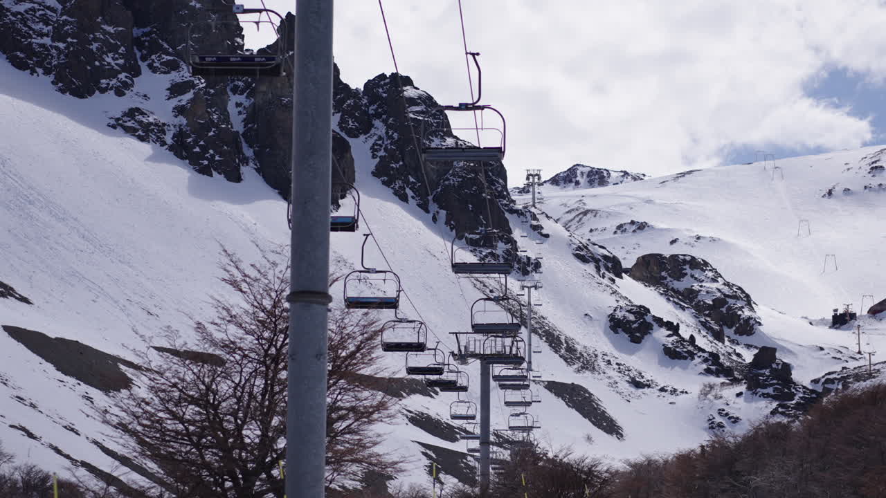 imagens de alta resolução de uma fileira de cadeiras de elevador de esqui subindo uma encosta de montanha coberta de neve em uma estação de esqui de inverno. a paisagem alpina acidentada, colinas cobertas de neve e infraestrutura de esqui.