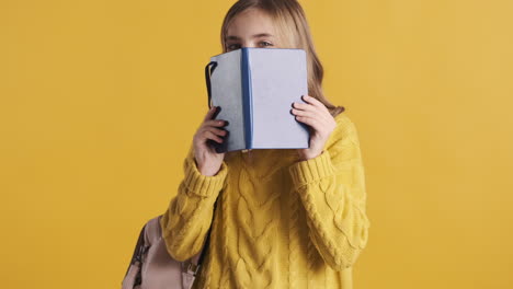 adolescente feliz estudiante caucásica con un cuaderno delante de su cabeza.