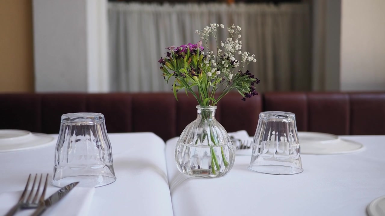 Pequeño jarrón de flores en una mesa de restaurante preparada