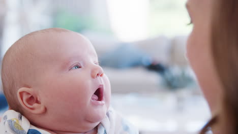 slow motion close up shot of mother sitting on sofa at home playing with baby son