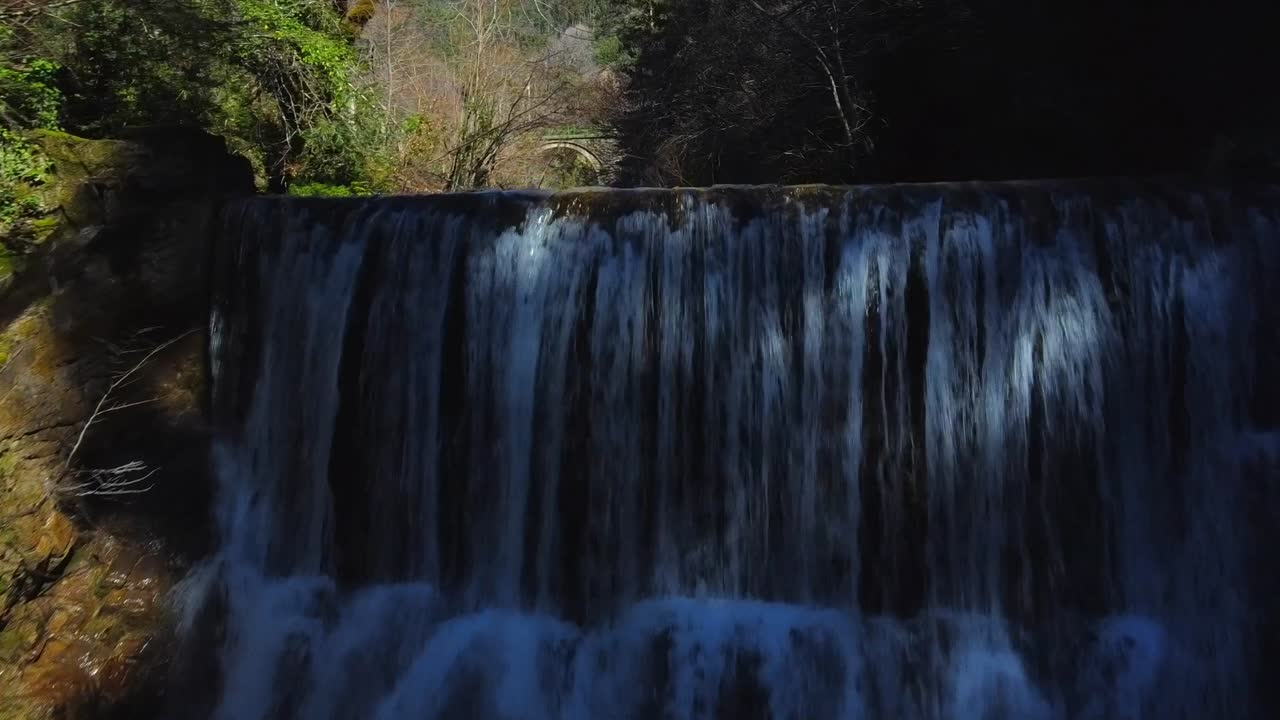 Aerial view of Labati, a waterfall in the spanish pyrenees, going back and forward in the dark forest. Near Aragües del puerto
