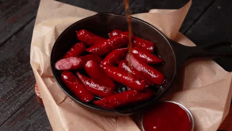 fried mini sausages in a cast iron pan with ketchup