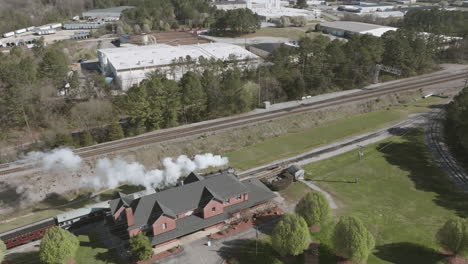 aerial drone shot of a steam train engine stopping at a train station in chattanooga, tn