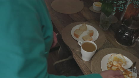 close-up of senior woman preparing meal in kitchen, focused on stirring ingredients with hand, wearing turquoise fleece. cozy kitchen environment with soft lighting, creating calm atmosphere