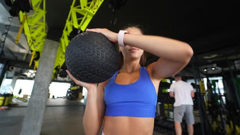 mujer haciendo ejercicio con una pelota de medicina en un gimnasio