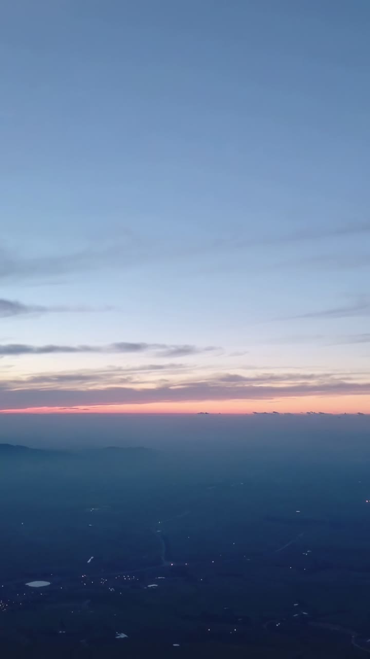 Vertikal video: Drone fanger rosa bånd ved daggry, soloppgang vises over tåkete landlys.