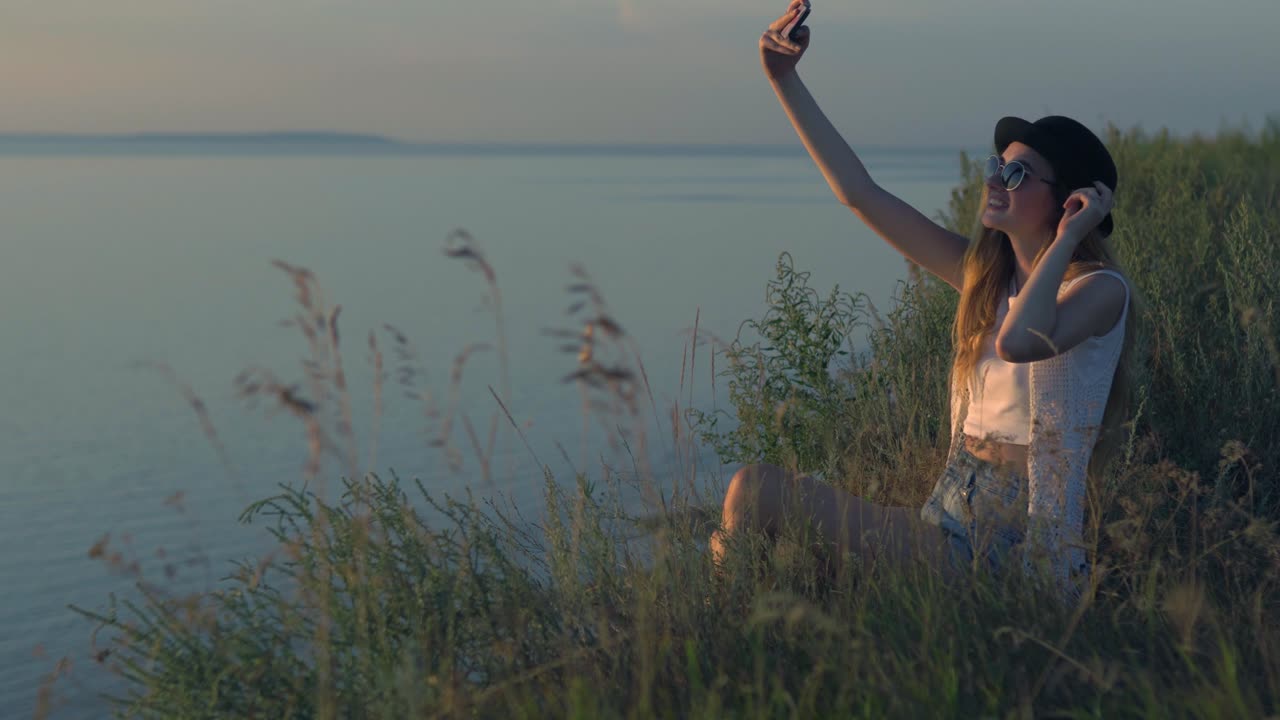 mujer tomando una selfie junto al río al atardecer