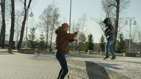 a father and son playing together outdoor as the punch the air playfully, with trees in the background