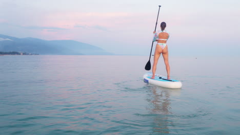 una mujer haciendo paddleboard al atardecer.