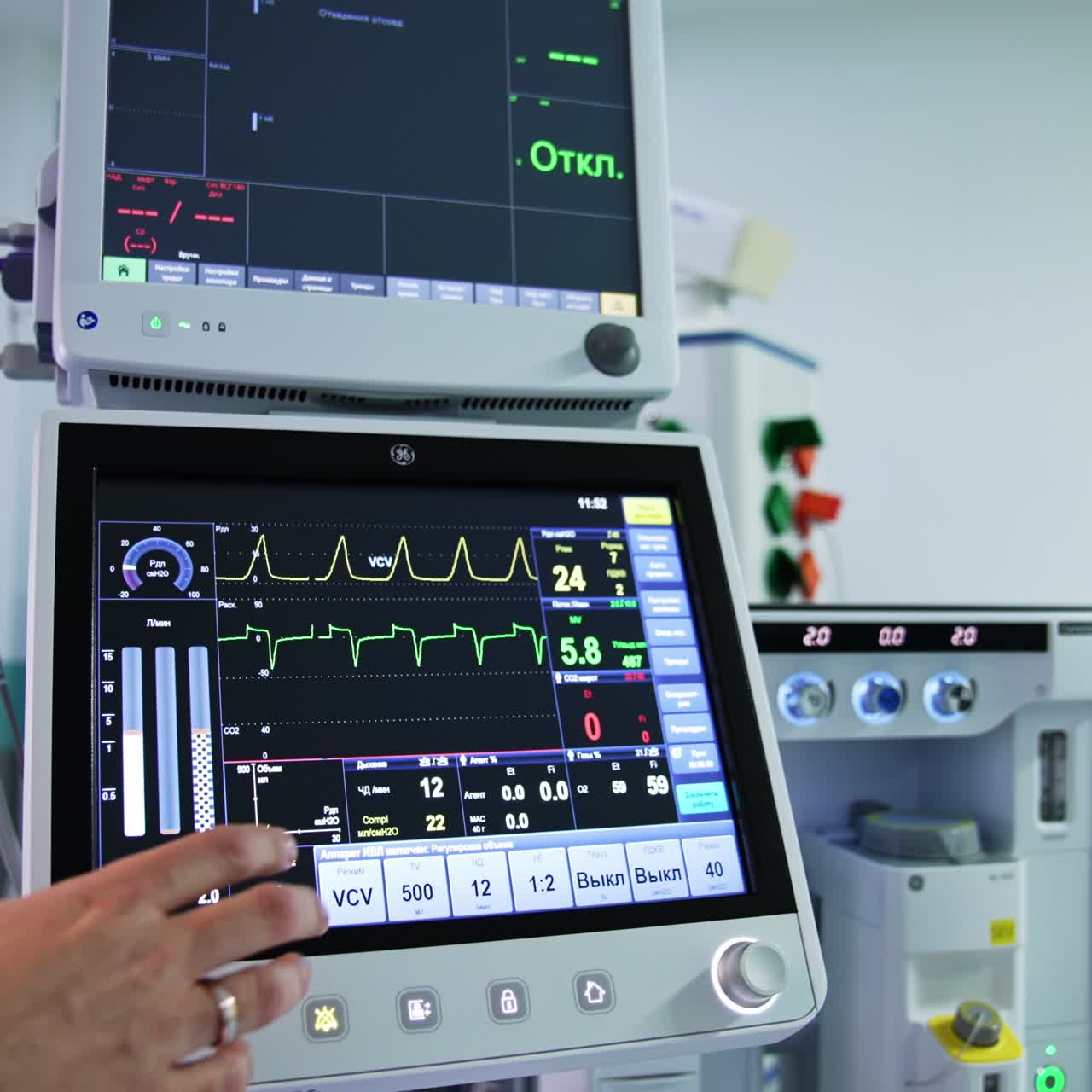 Two monitors from advanced lung ventilation apparatus in the surgery room. Male hand of medic pointing at machine and its sensors
