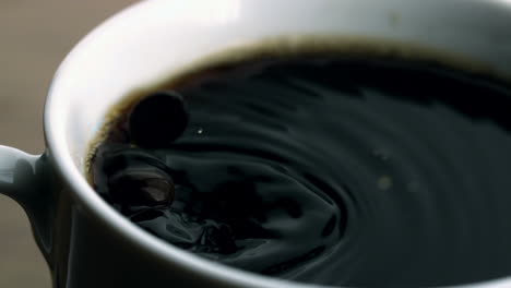 beans falling into cup of coffee