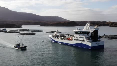 drone shot of a fishing boat driving past a hebridean fish farming vessel