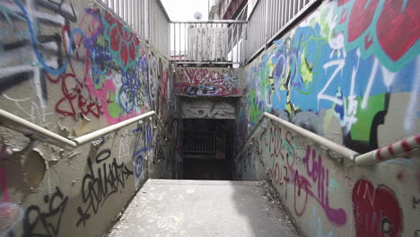 dolly forward through stairs leading to a tunnel with graffiti on walls