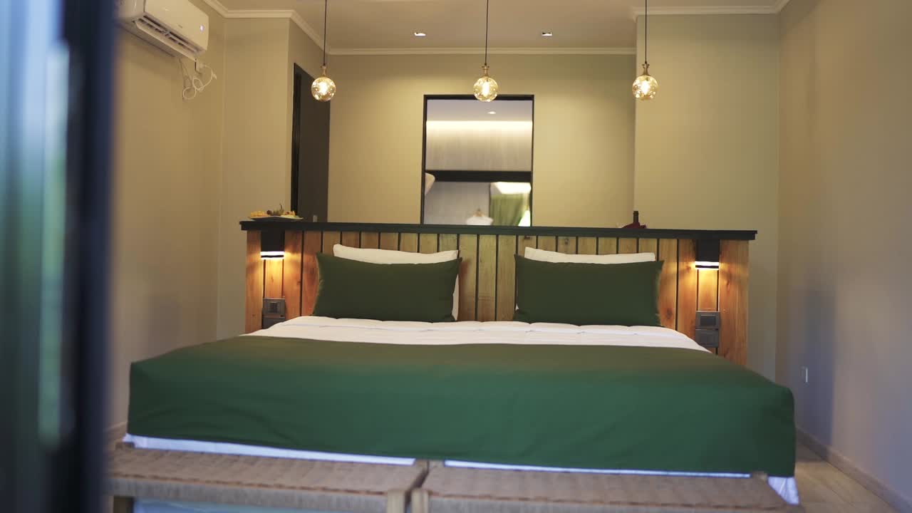 Camera da letto con letto king size verde e testiera in legno in una lussuosa camera d'albergo. Attività ricettiva