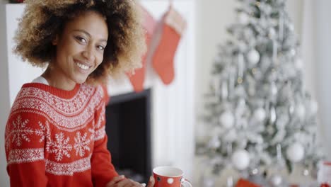mujer sonriente bebiendo una taza de café navideño