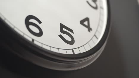 white clock face close up in time lapse on dark grey wall