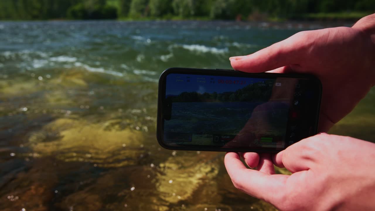 Mãos segurando smartphone com visualização ao vivo do rio por drone