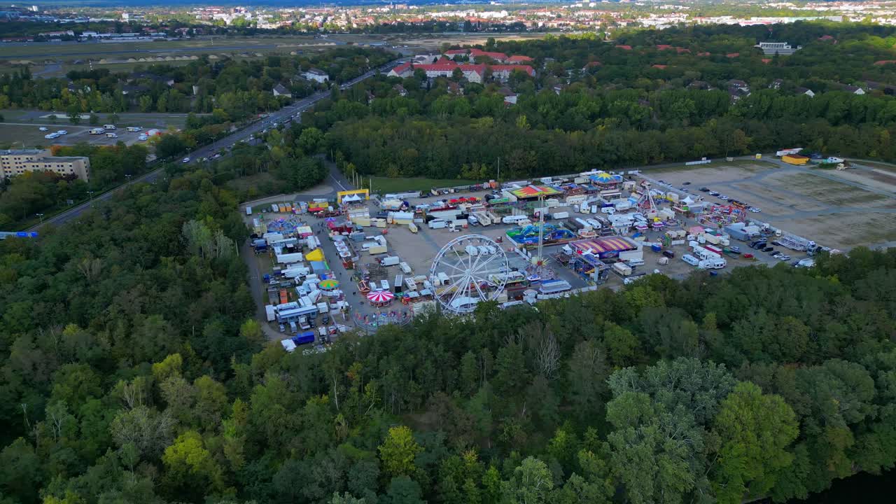 Berlin funfair showing a Ferris wheel, amusement rides, and various stalls from an aerial perspective. Smooth aerial view flight speed ramp hyper motion time lapse panorama orbit drone