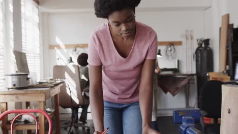 busy african american female worker talking on smartphone in jewellery studio in slow motion