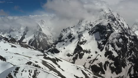 vuelo aéreo a través de nubes montañosas sobre hermosos picos nevados de montañas y glaciares.