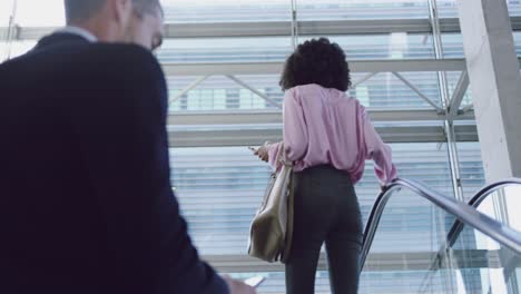 businesswoman using mobile phone on escalator in a modern office 4k