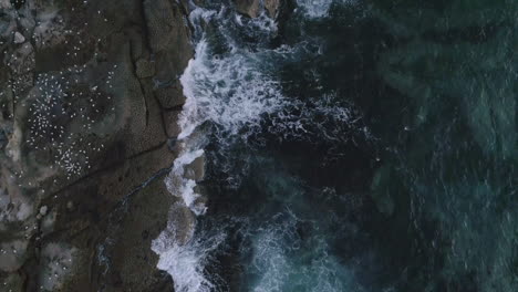 Vista-Aérea-De-Las-Olas-Del-Océano-Rompiendo-En-La-Costa-Rocosa