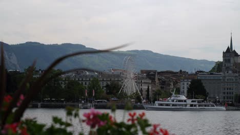 a ferris wheel spinning in the distance on a river in geneva, switzerland